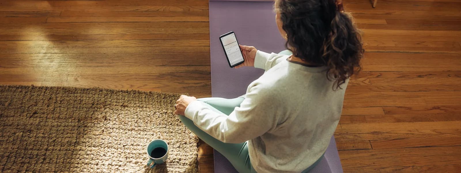Woman doing yoga at home with a phone nearby for fitness tracking
