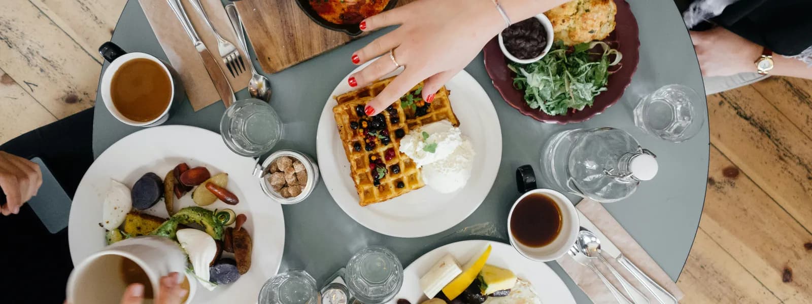 Overhead view of a brunch table with waffles, coffee, and fresh food
